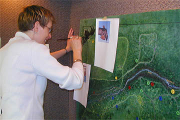 Laura Kerr works on the new mural of Waterman Center's hiking trails.